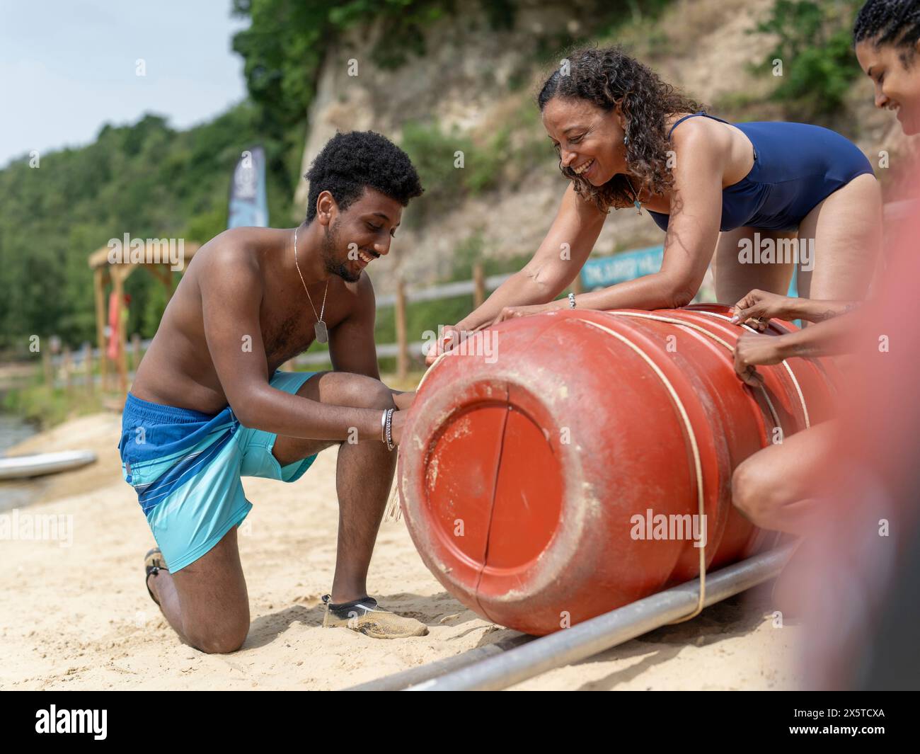 Friends building raft from barrels and ropes on beach Stock Photo - Alamy