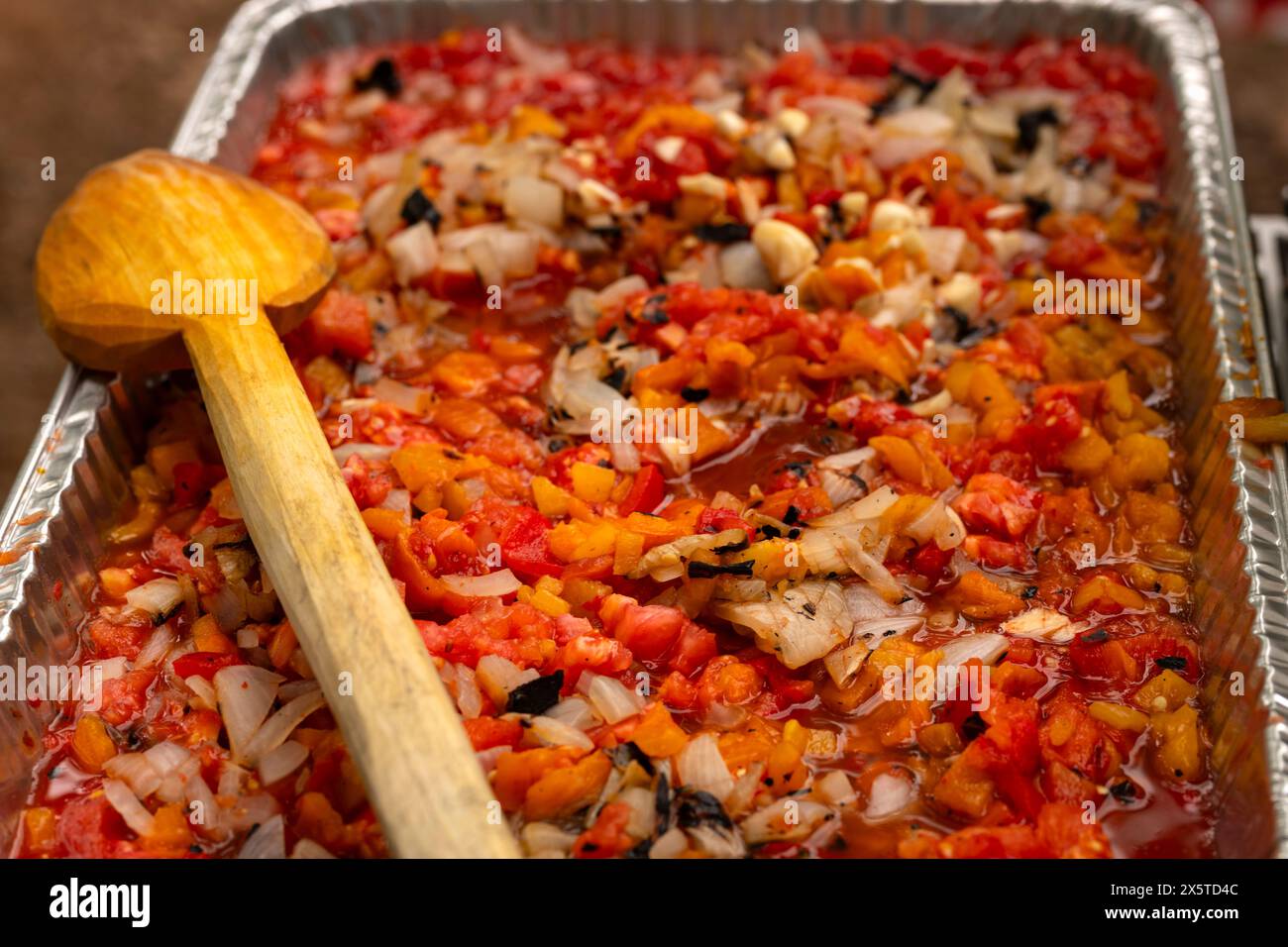 Roasted salsa with spices, peppers, onions, garlic, and tomatoes in an aluminum steam table pan. Party catering concept. Stock Photo