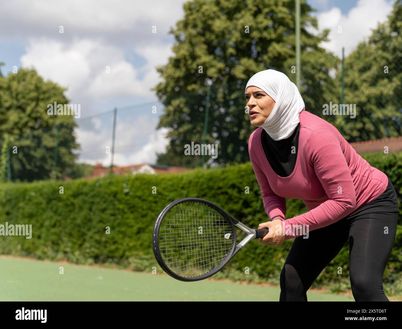 UK,Sutton,Woman in headscarf playing tennis in park Stock Photo