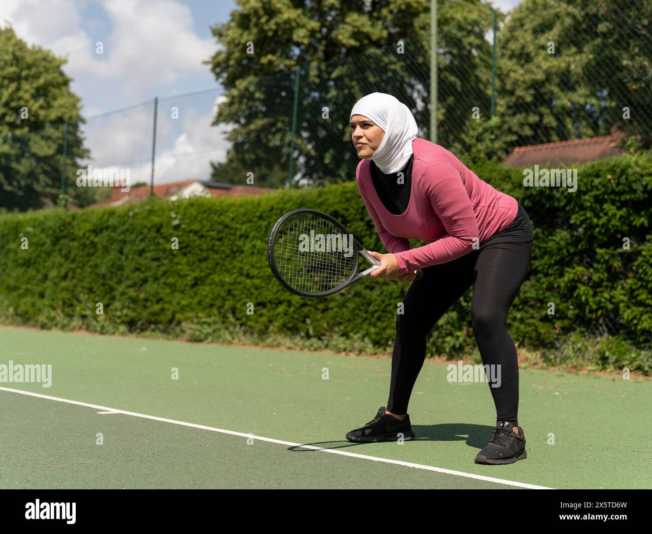 UK,Sutton,Woman in headscarf playing tennis in park Stock Photo