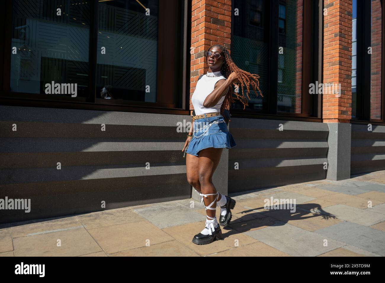 Woman wearing mini skirt and white top walking on sidewalk Stock Photo ...