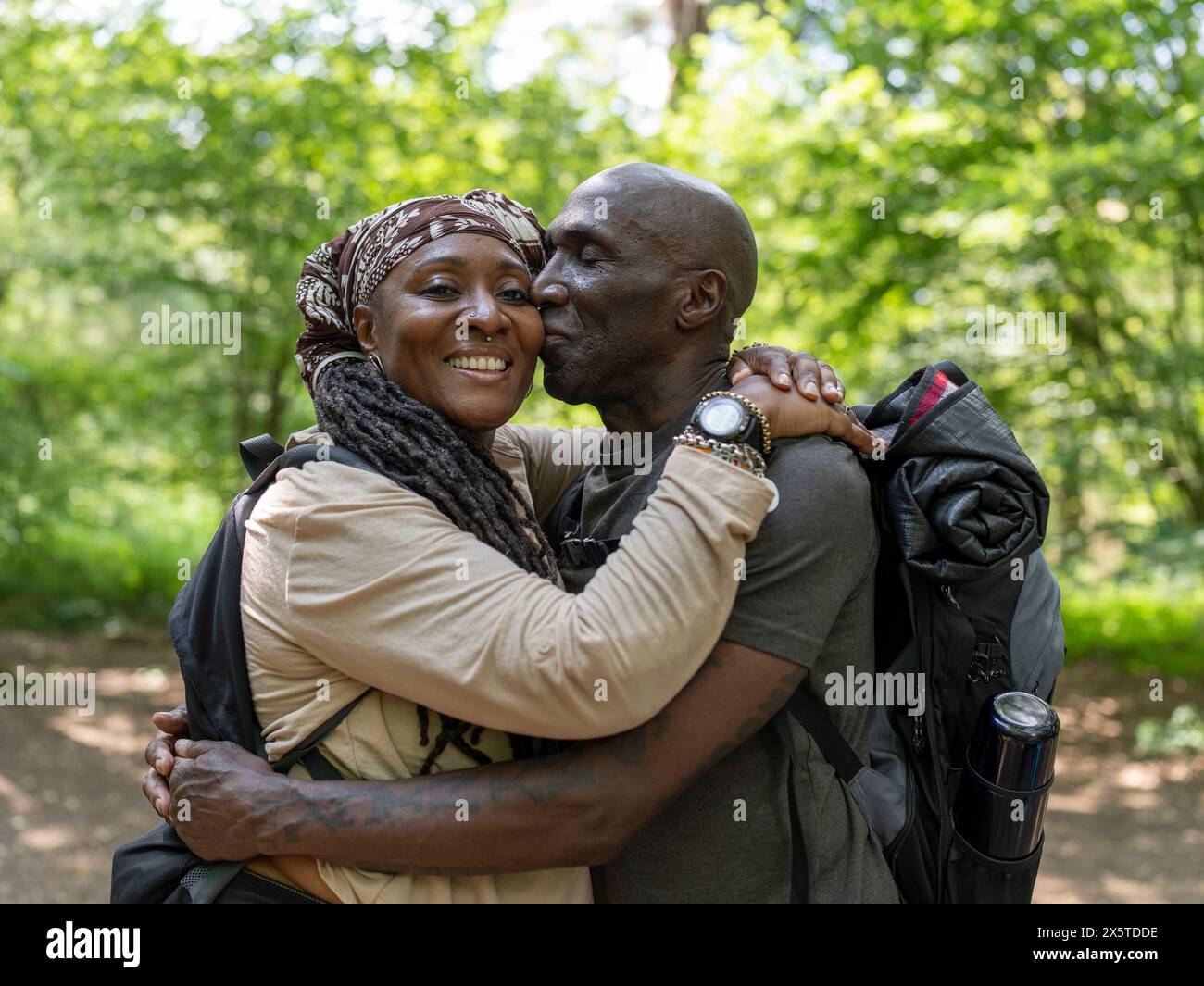 Portrait of smiling hiking couple hugging in forest Stock Photo - Alamy