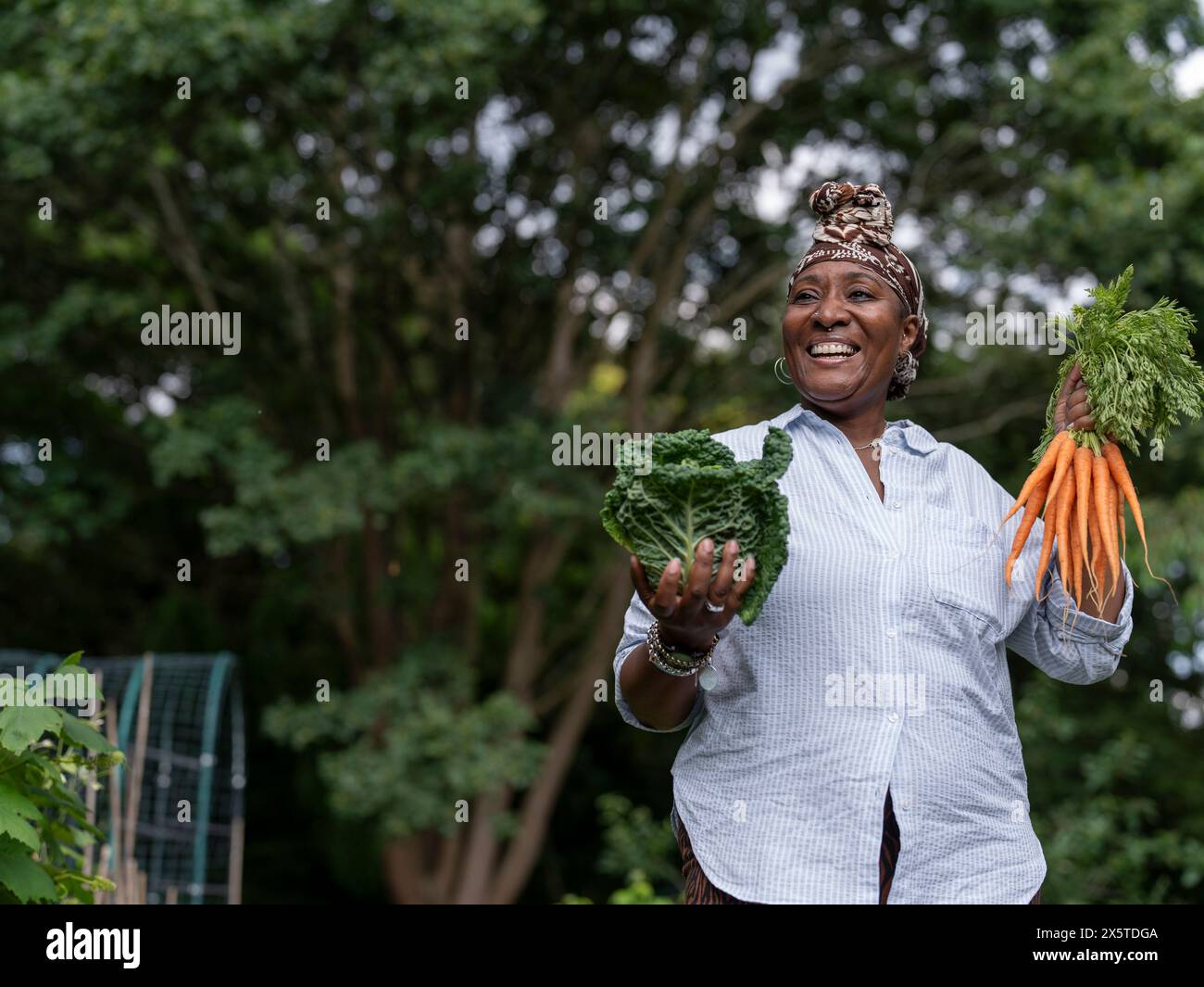 Smiling mature woman holding vegetables in allotment Stock Photo - Alamy