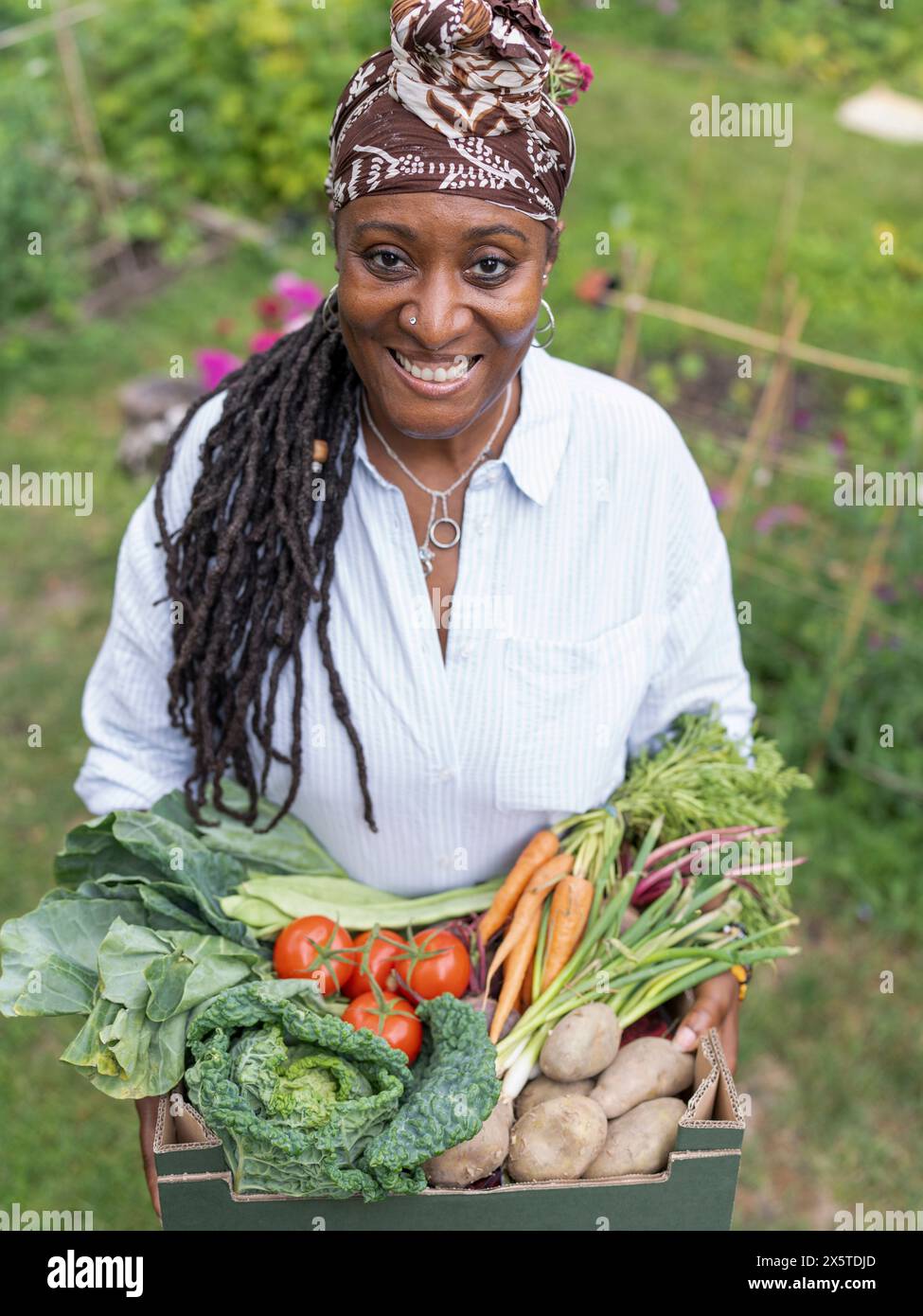 Portrait of smiling mature woman holding vegetables from garden Stock ...
