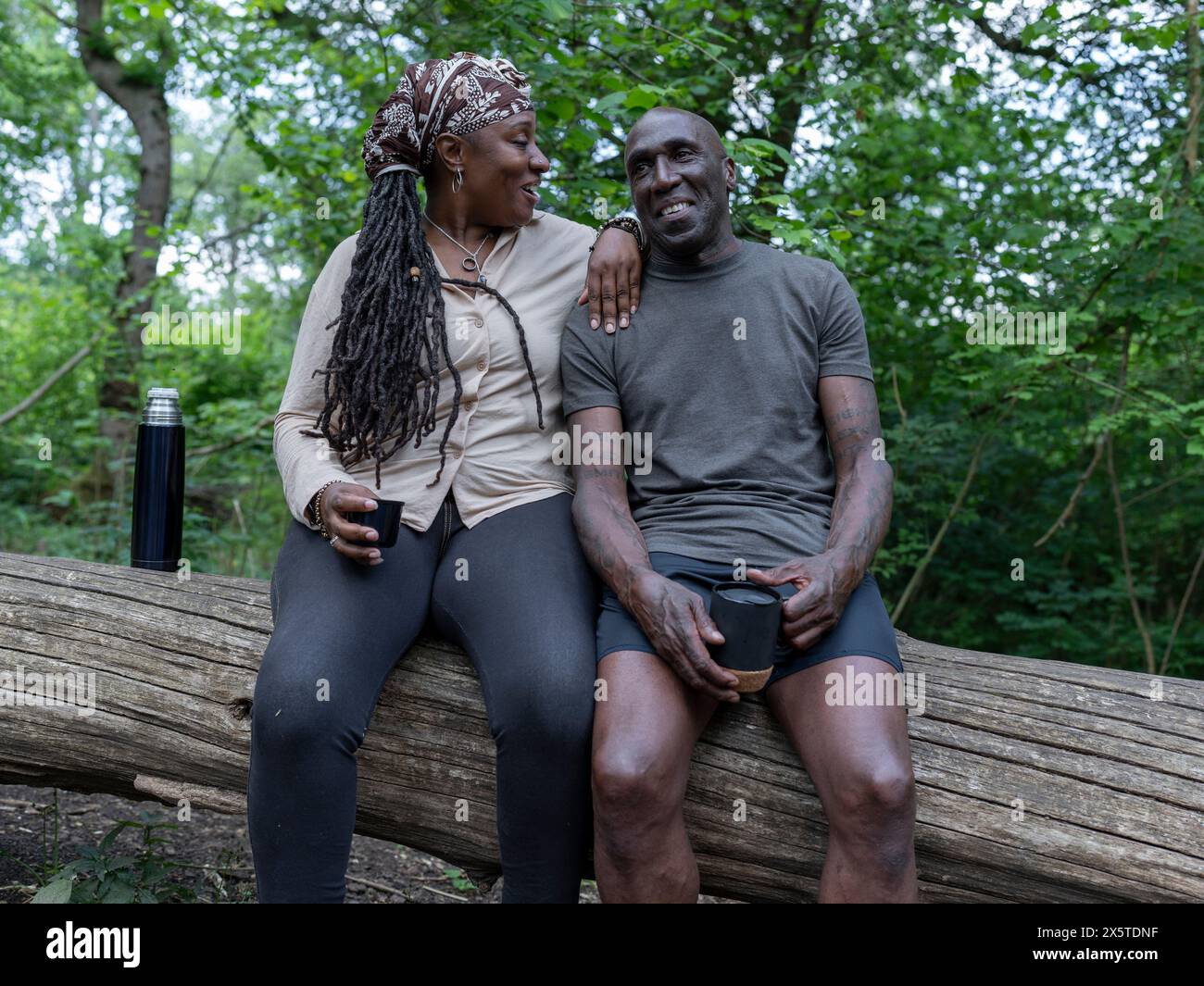 Mature couple resting on log on hike Stock Photo