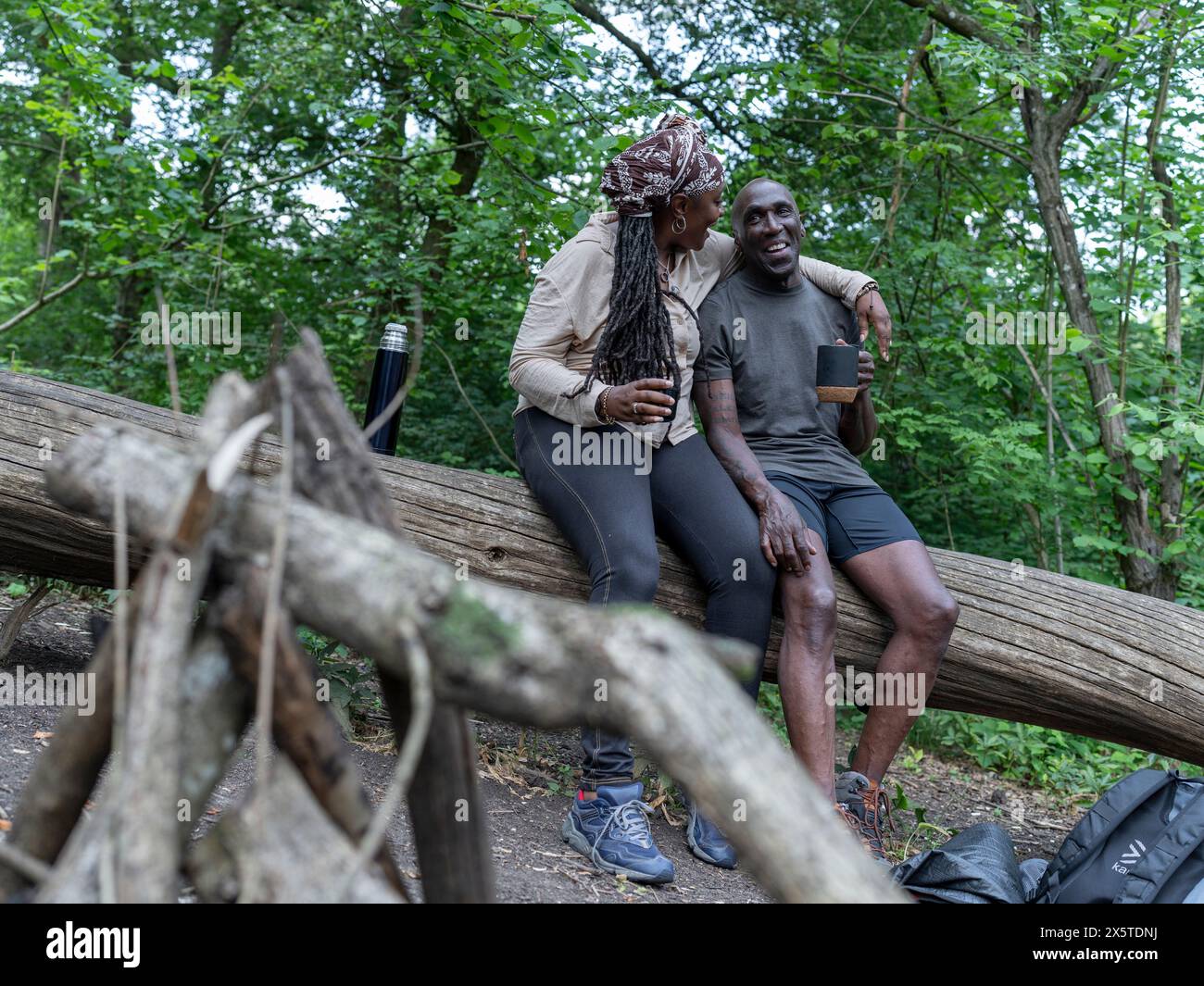 Mature couple resting on log on hike Stock Photo