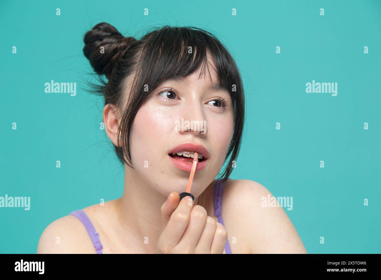 Studio portrait of girl applying lip gloss Stock Photo