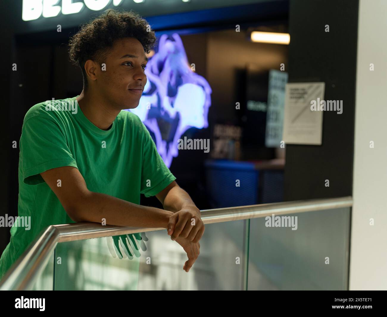 Young man looking away while leaning on glass railing Stock Photo
