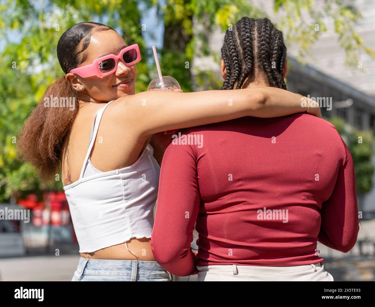 Portrait of smiling woman embracing friend on sunny day Stock Photo