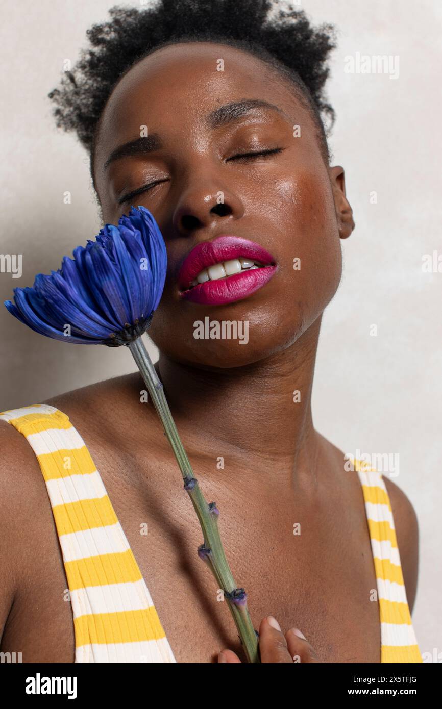Portrait of woman with closed eyes holding blue flower Stock Photo - Alamy