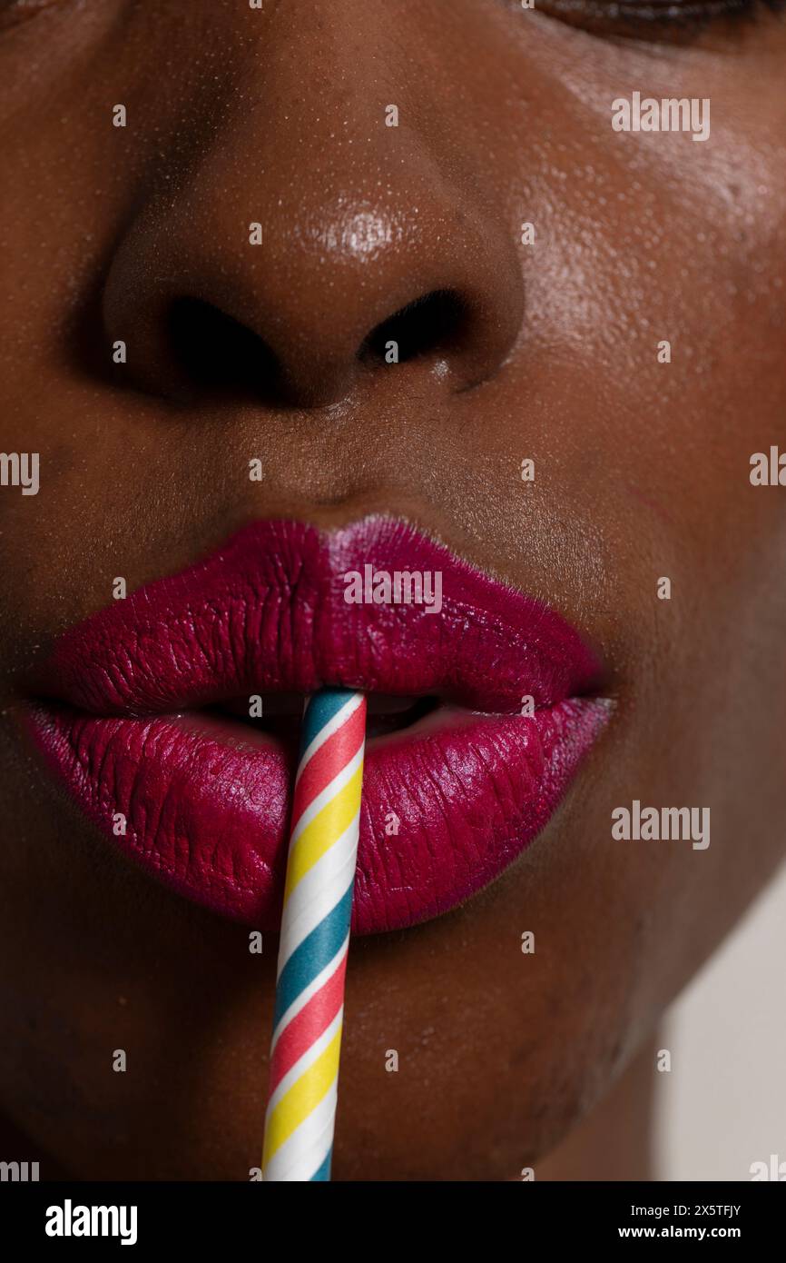 Woman wearing red lipstick using drinking straw Stock Photo