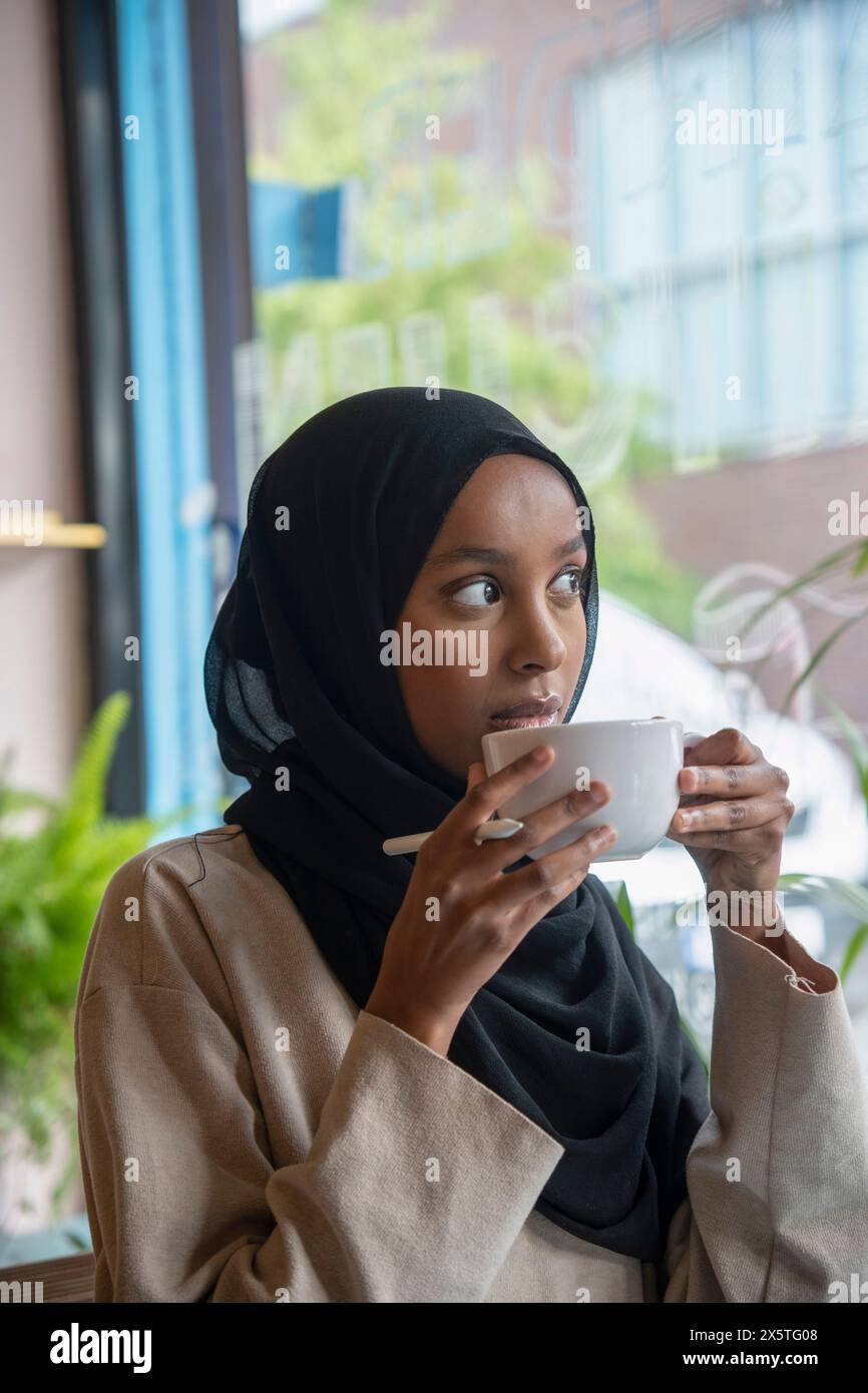Young woman in hijab drinking coffee in cafe Stock Photo - Alamy