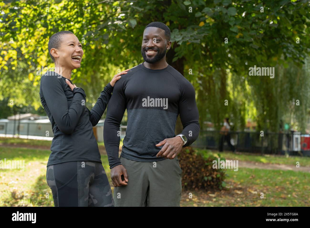 Smiling athletic man and woman standing in park Stock Photo