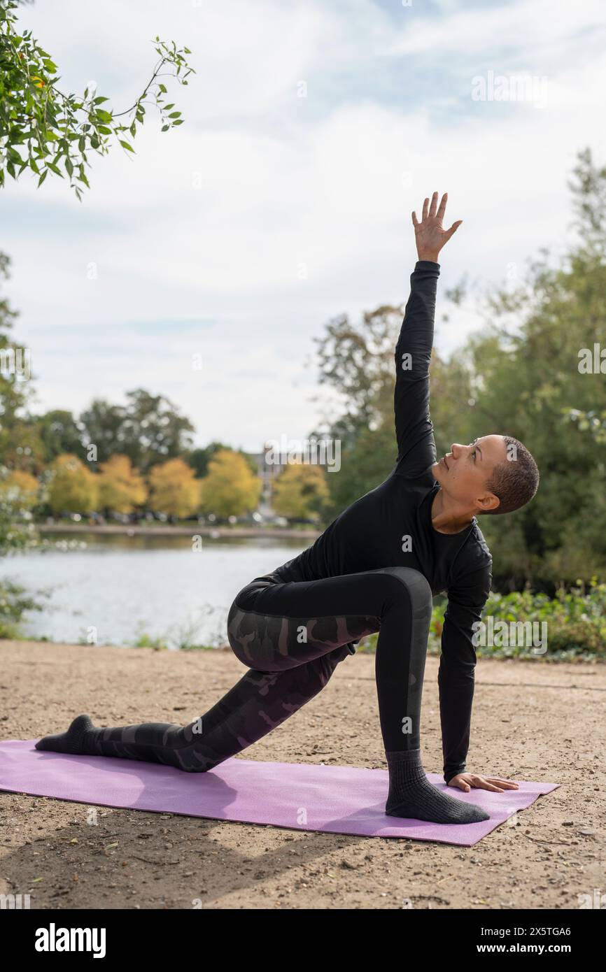 Woman in twisting lunge pose in park Stock Photo
