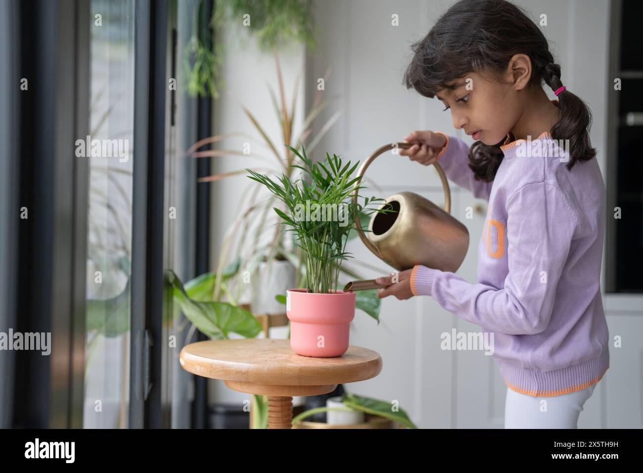 Little girl watering plant at home Stock Photo