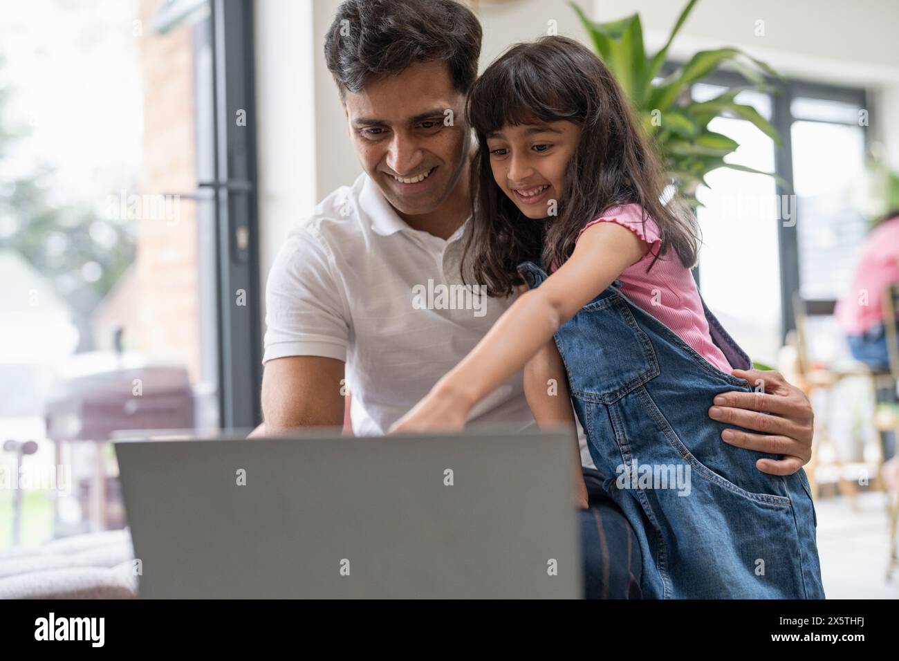 Father sitting with daughter and using laptop Stock Photo