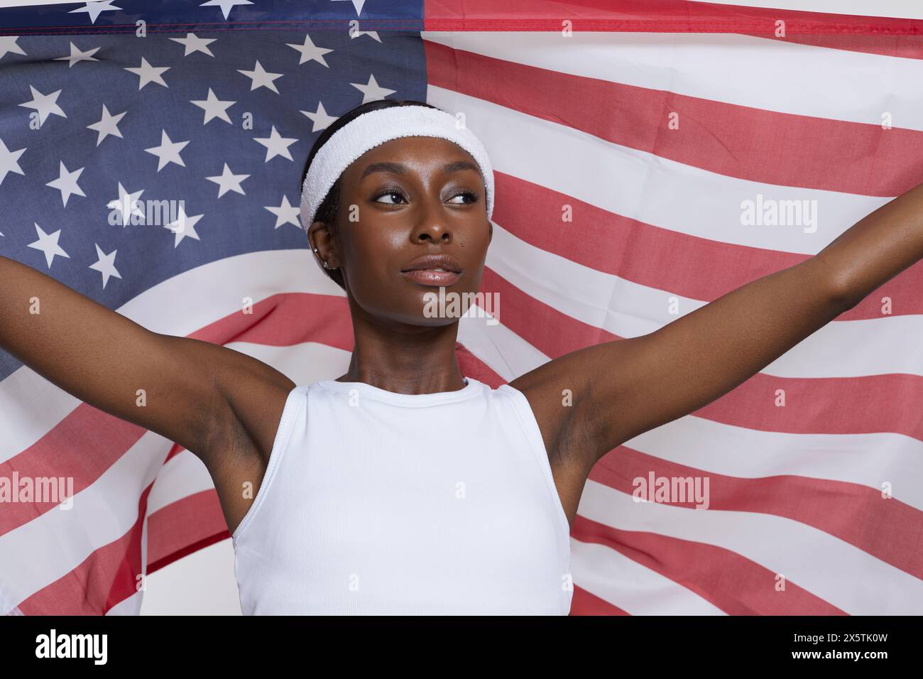 Studio portrait of athletic woman in sports clothing holding American ...