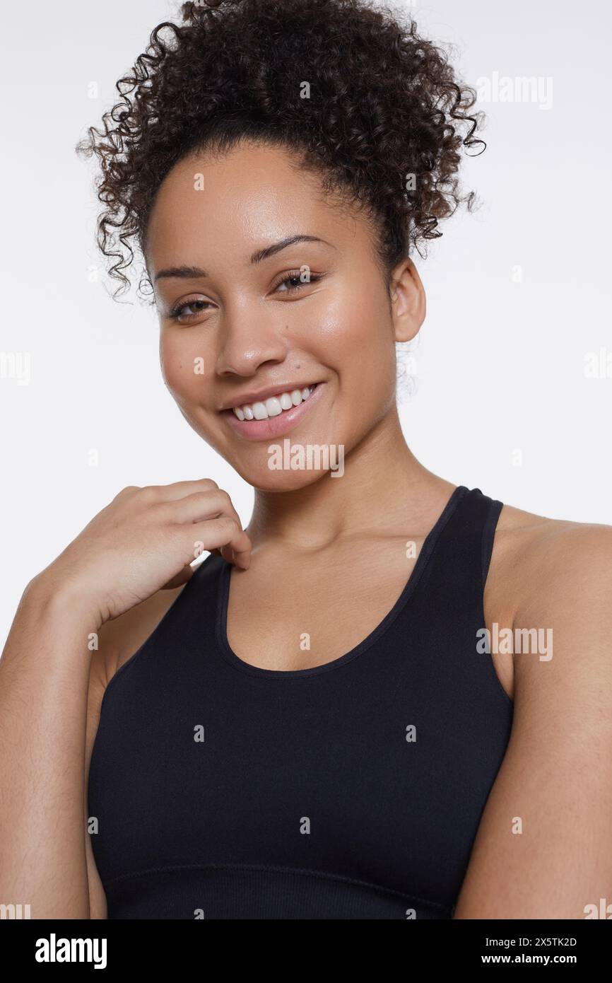 Studio portrait of smiling athletic woman in black top Stock Photo
