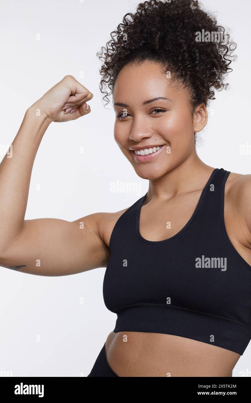 Studio portrait of smiling athletic woman flexing muscles Stock Photo