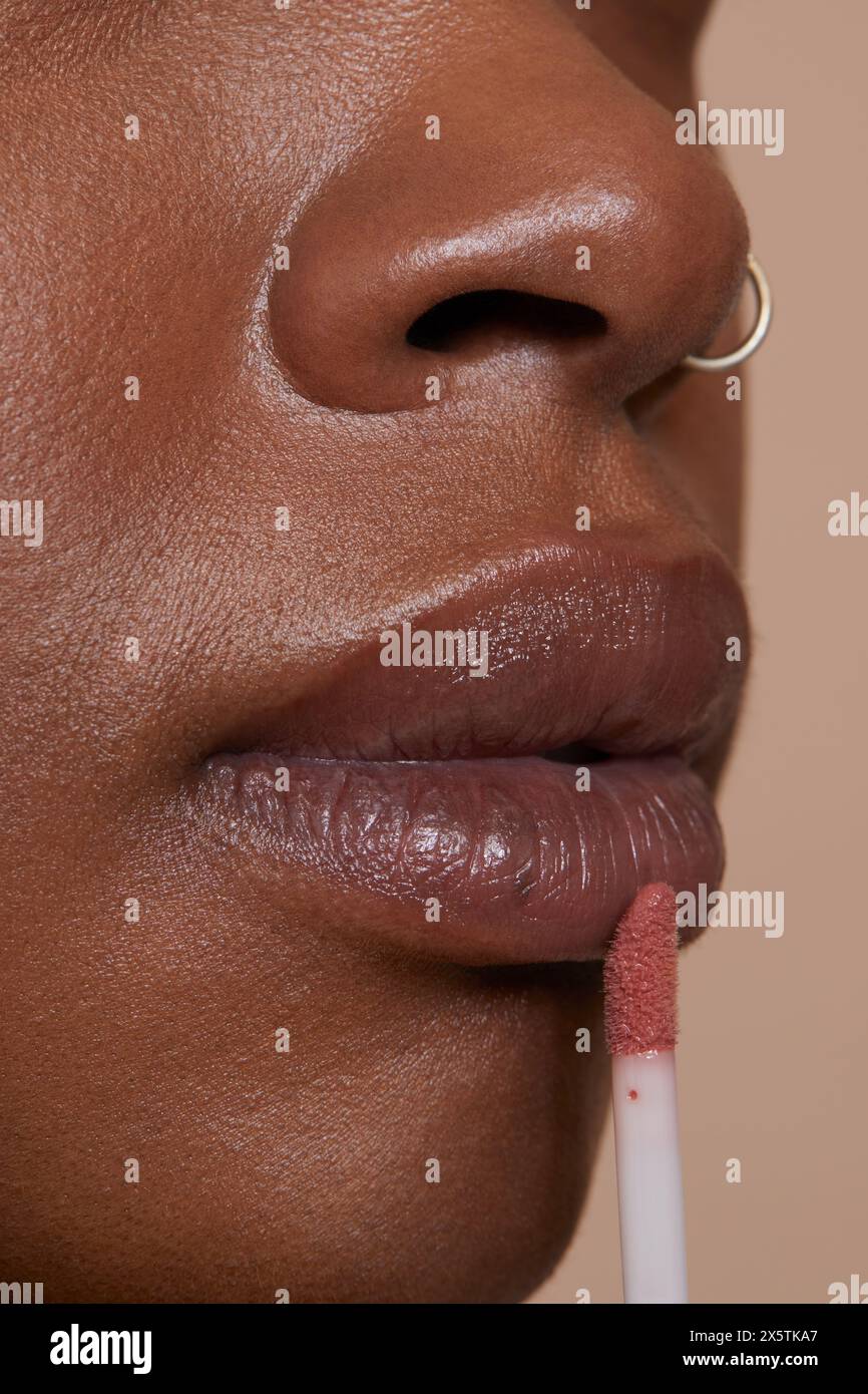 Close-up of woman applying lip gloss Stock Photo