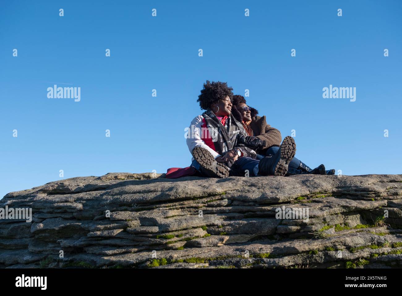Two women relaxing on top of rock Stock Photo - Alamy