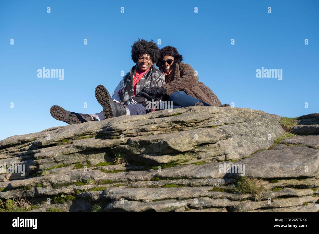Two women relaxing on top of rock Stock Photo - Alamy