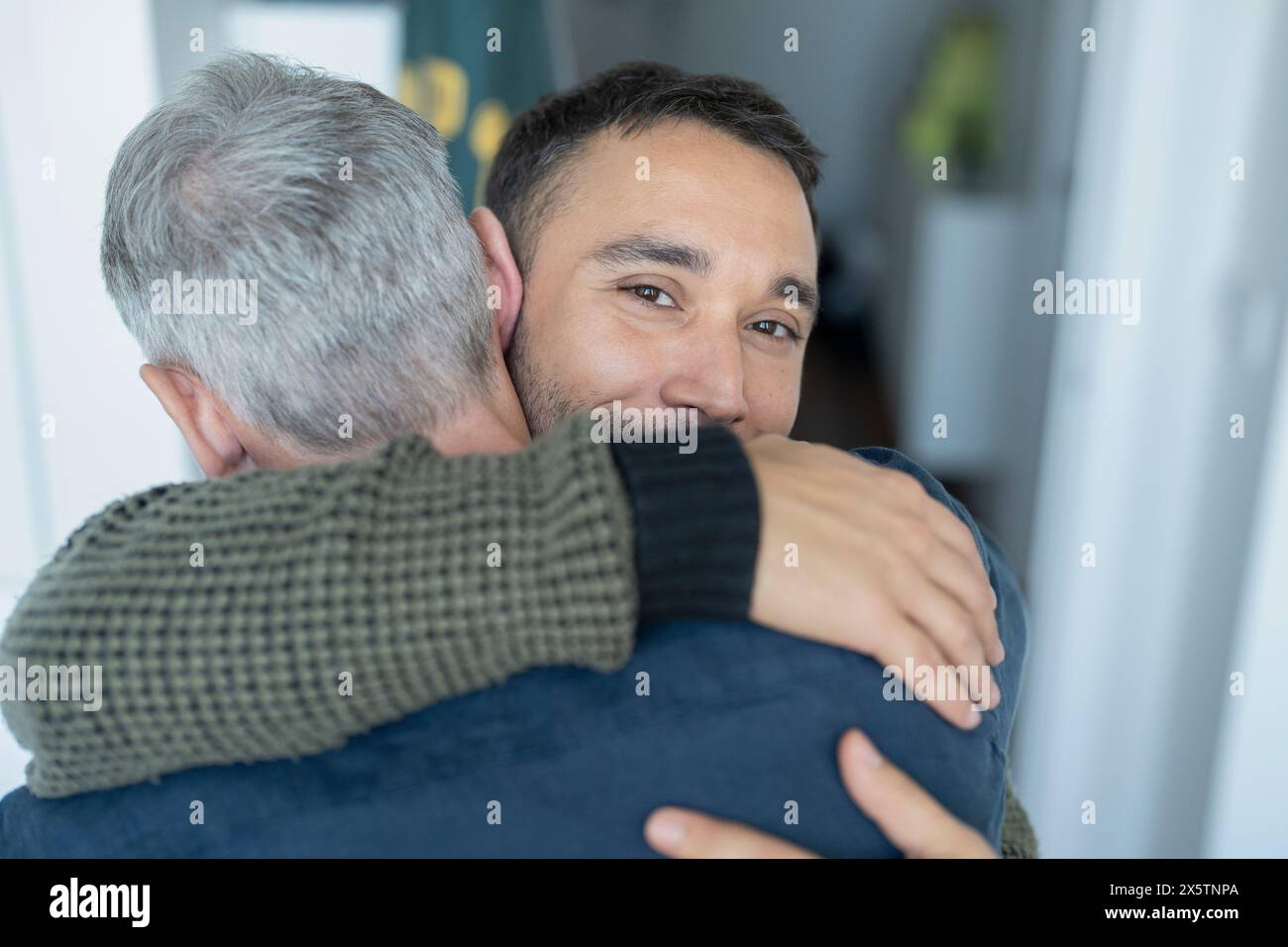 Male couple hugging at home Stock Photo - Alamy