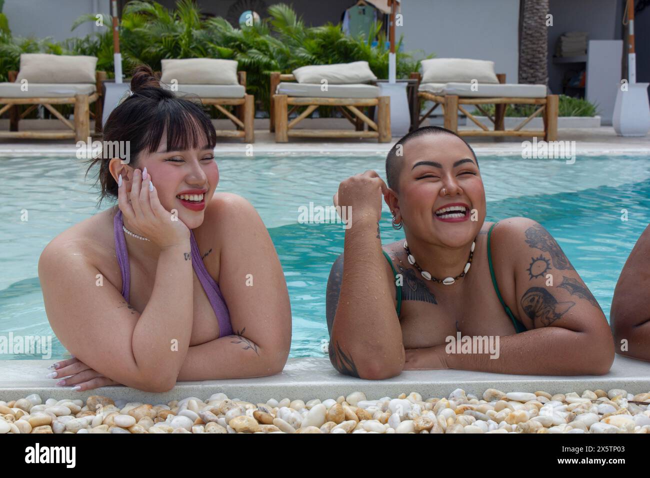 Two cheerful women relaxing on poolside Stock Photo