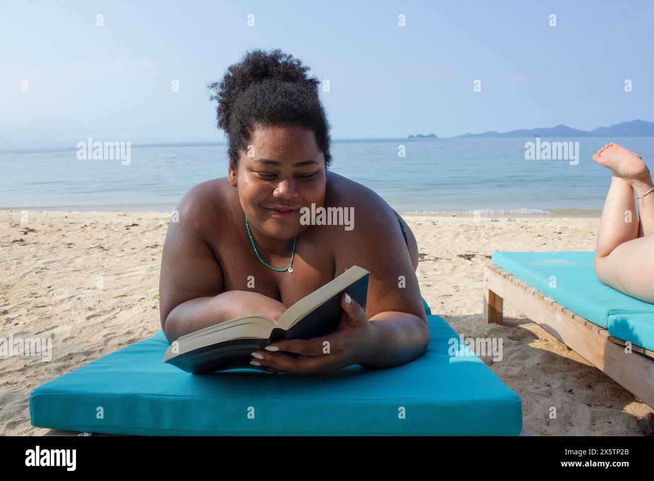 Young woman relaxing and reading on beach Stock Photo