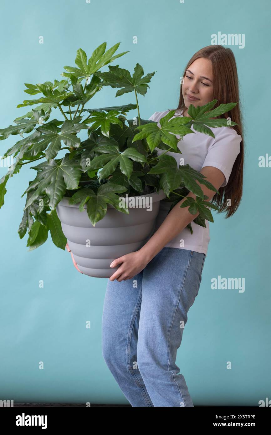 Studio portrait of teenage girl holding large potted plant Stock Photo ...