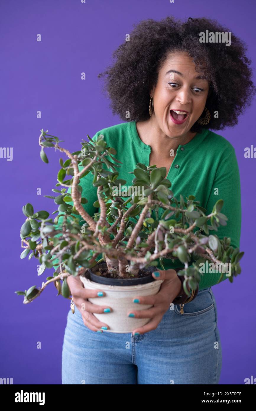 Studio portrait of smiling woman holding potted plant Stock Photo - Alamy