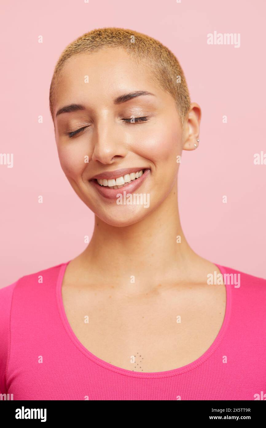 Portrait of smiling woman with short blond hairstyle and closed eyes ...