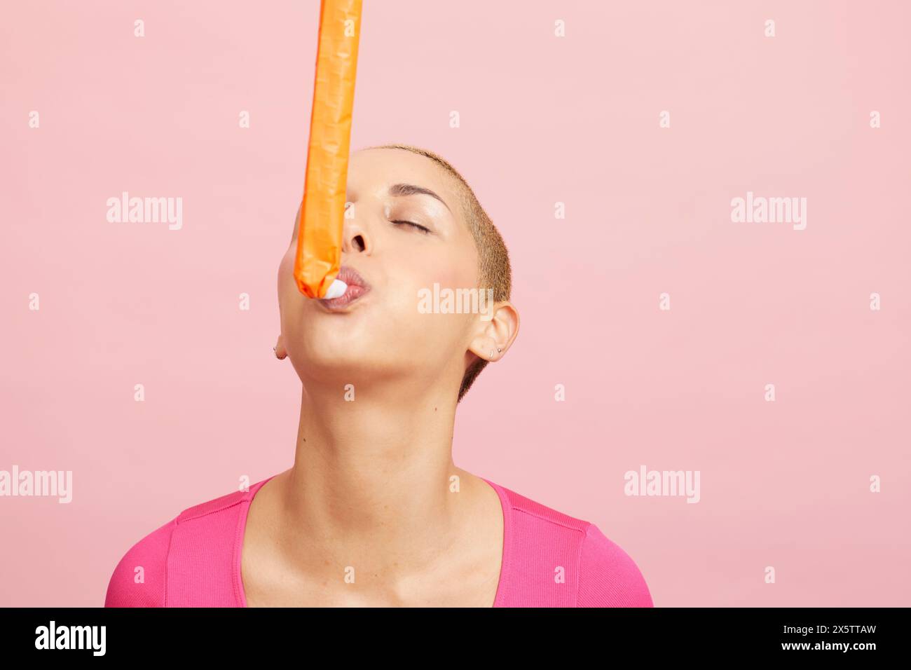Young blond woman blowing party horn Stock Photo - Alamy