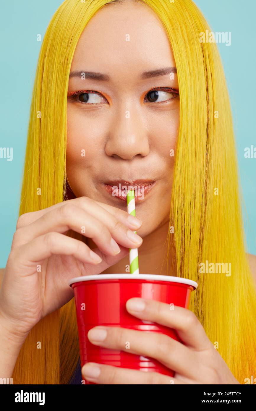 Young woman with long yellow hair, drinking through straw Stock Photo Alamy