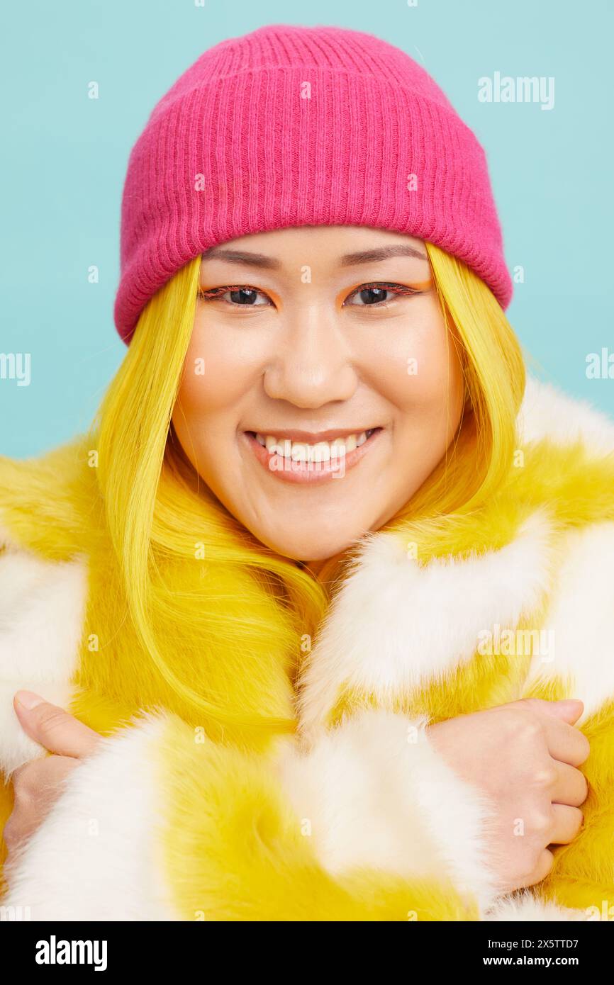 Woman with long yellow hair, wearing fur coat and pink knit hat Stock Photo