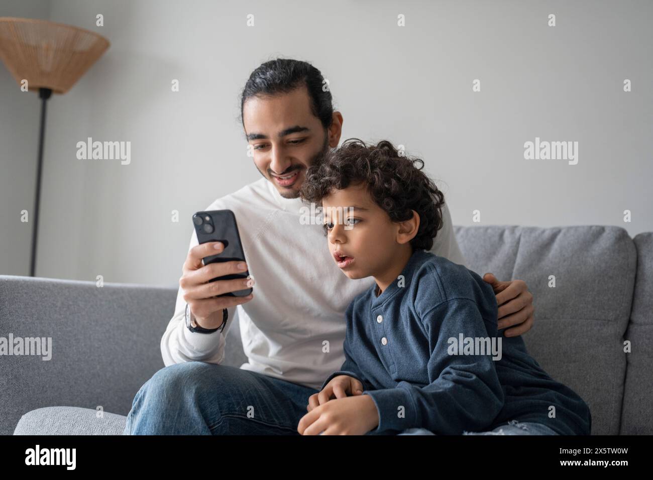 Father and son (6-7) using smart phone at home Stock Photo