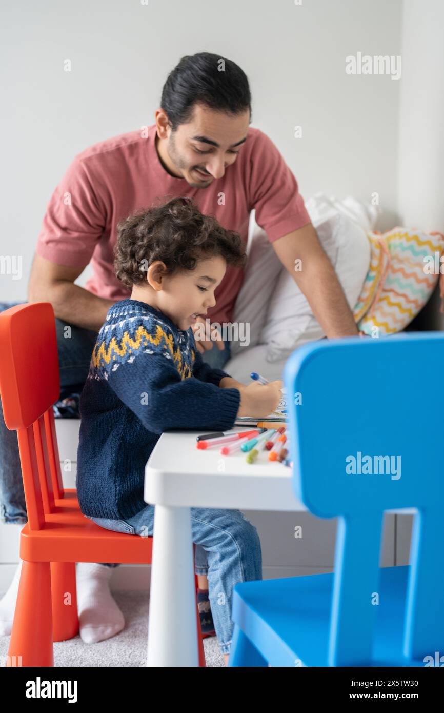 Father and son (2-3) coloring in coloring book at home Stock Photo