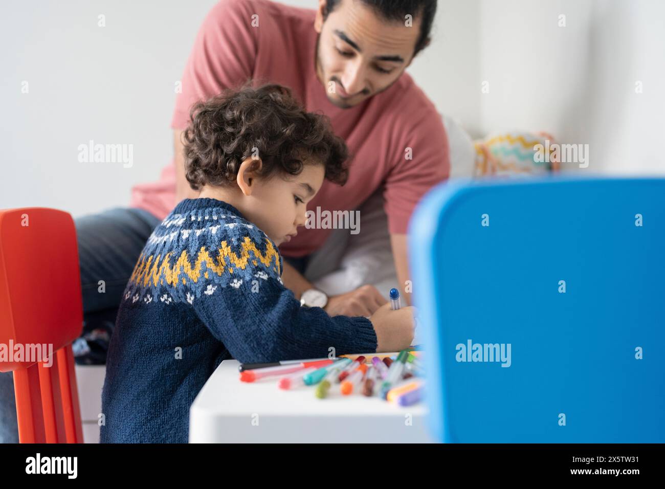 Father and son (2-3) coloring in coloring book at home Stock Photo
