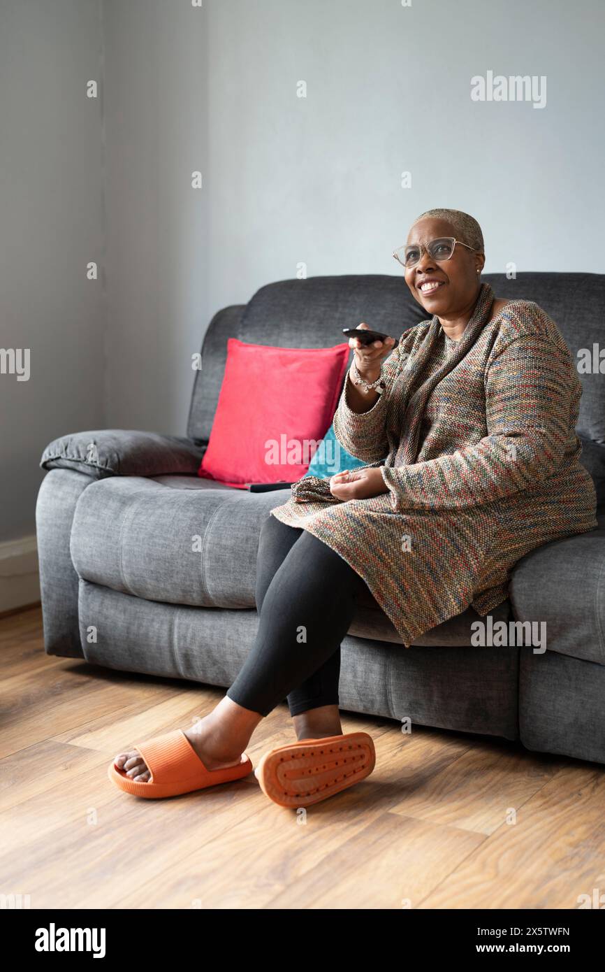 Mature woman sitting in living room and watching TV Stock Photo - Alamy