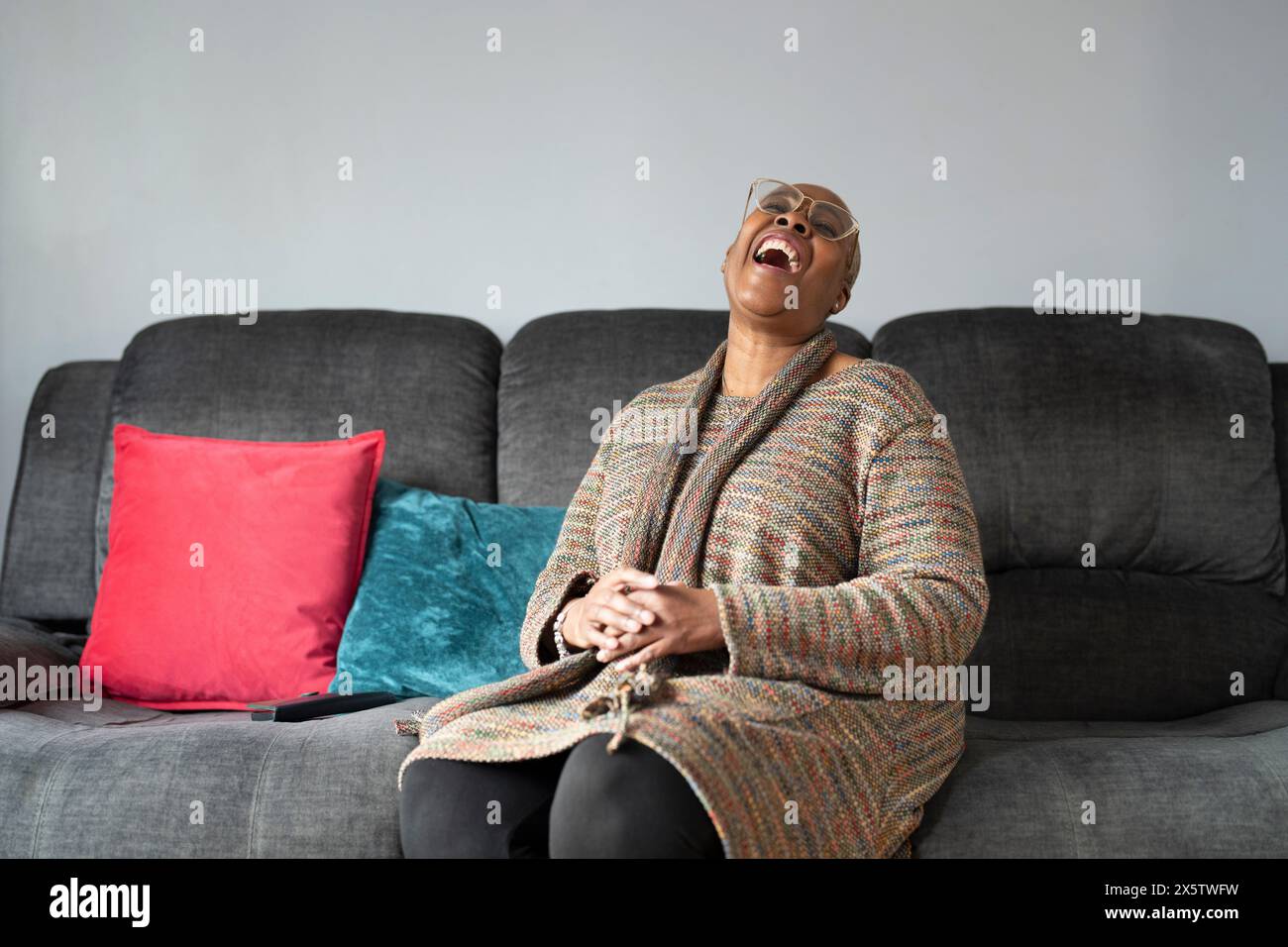 Mature woman sitting in living room and laughing Stock Photo - Alamy