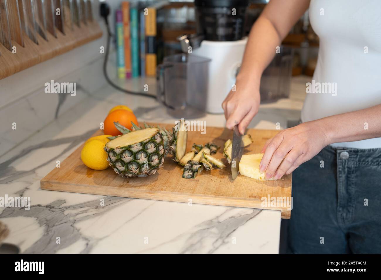 Woman slicing fruit in kitchen, midsection Stock Photo