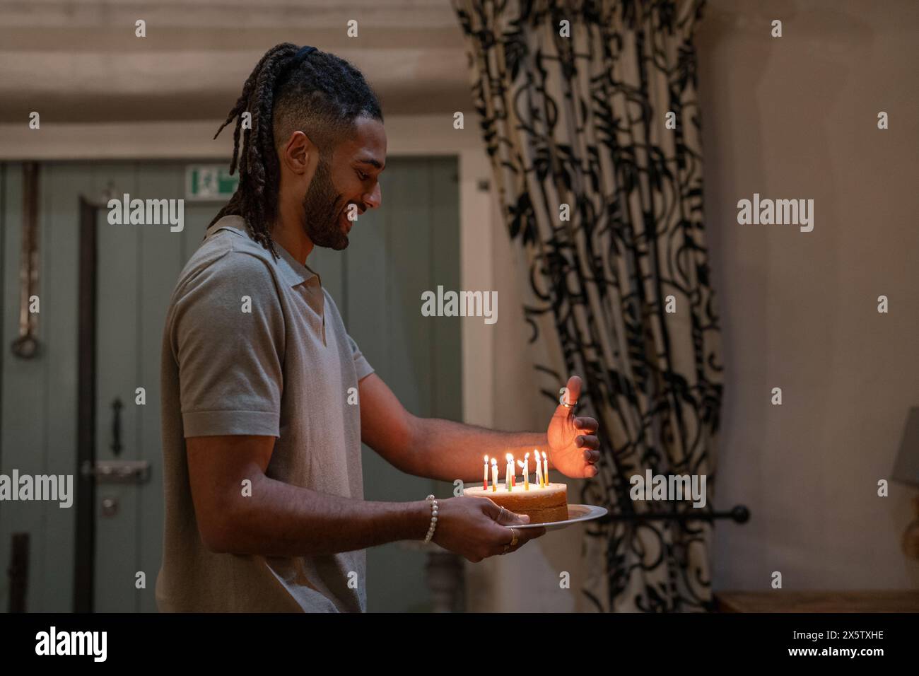 Man holds plate with birthday cake and candles Stock Photo