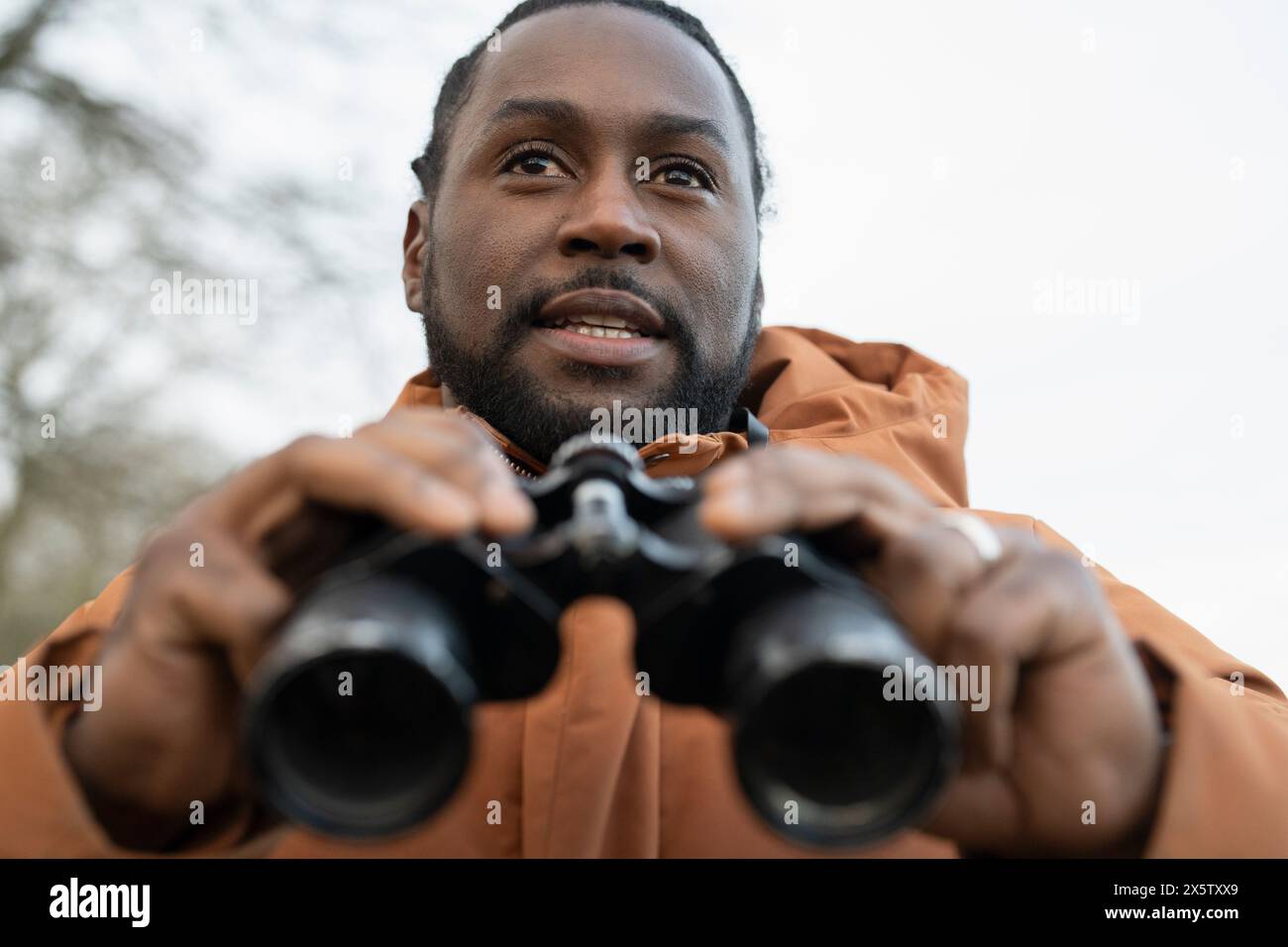 Man looking through binoculars in rural area Stock Photo