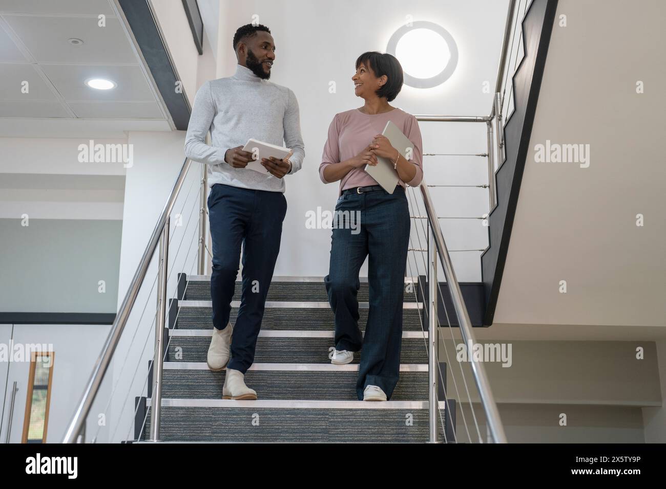 Business people walking down stairs and talking in office Stock Photo ...