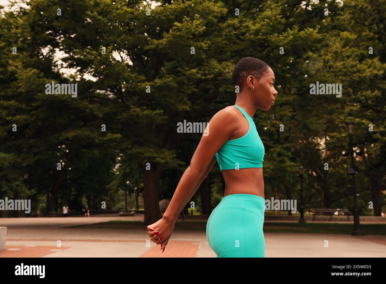 Profile of woman in sports clothing stretching in park Stock Photo