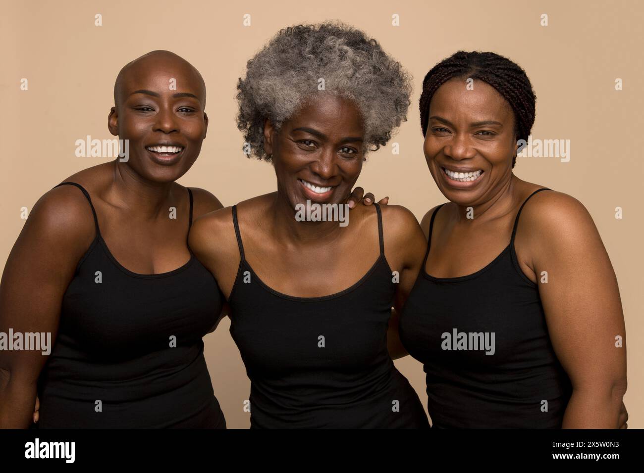 Studio portrait of three smiling women in black tops Stock Photo