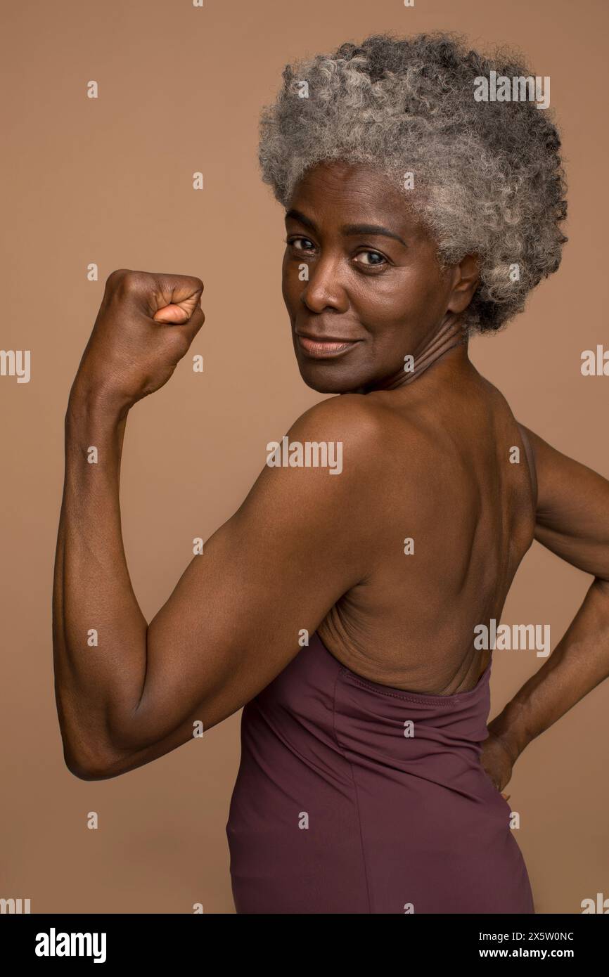 Portrait of senior woman flexing muscles Stock Photo