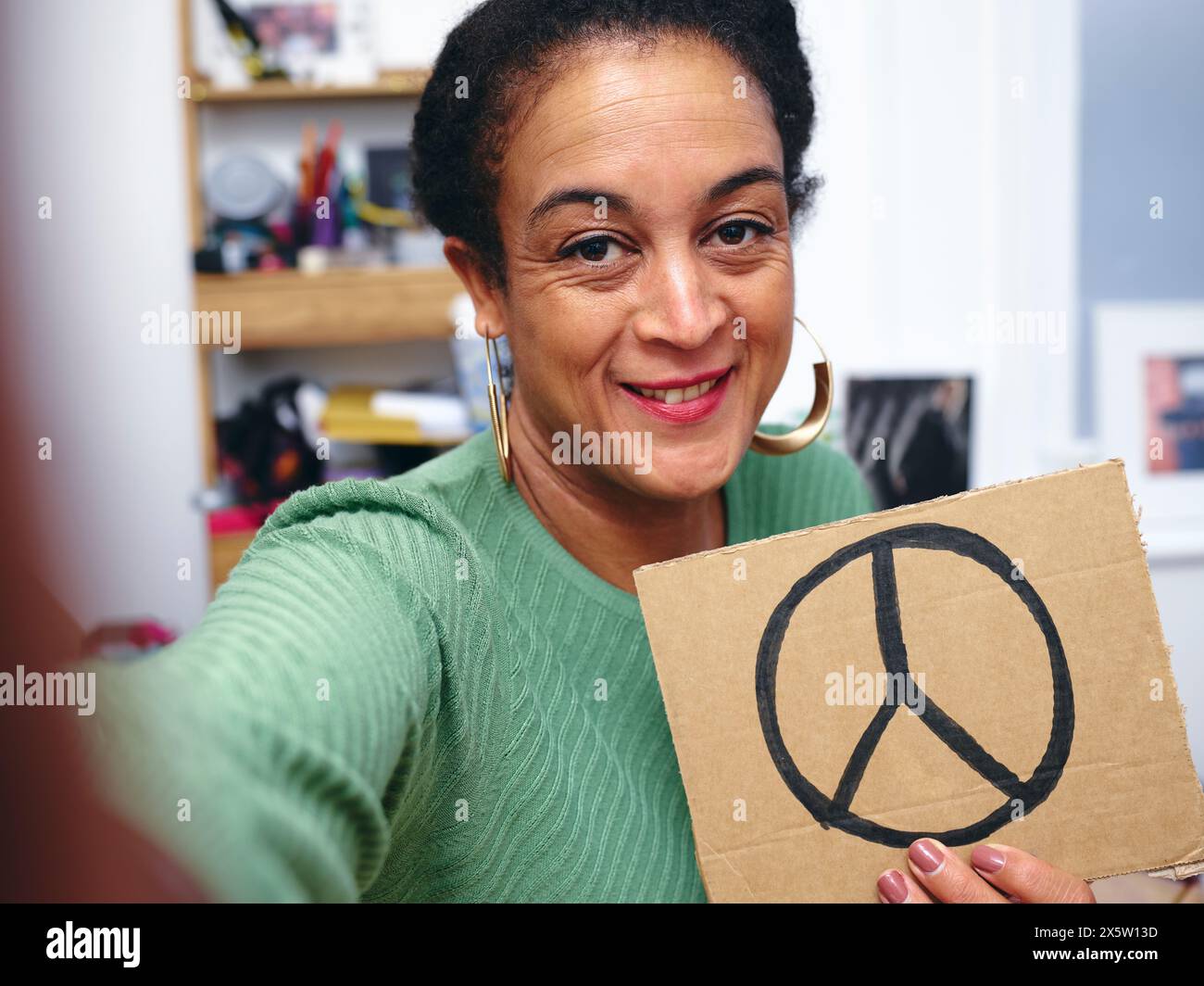 Woman in room holding protest sign with symbol of peace Stock Photo