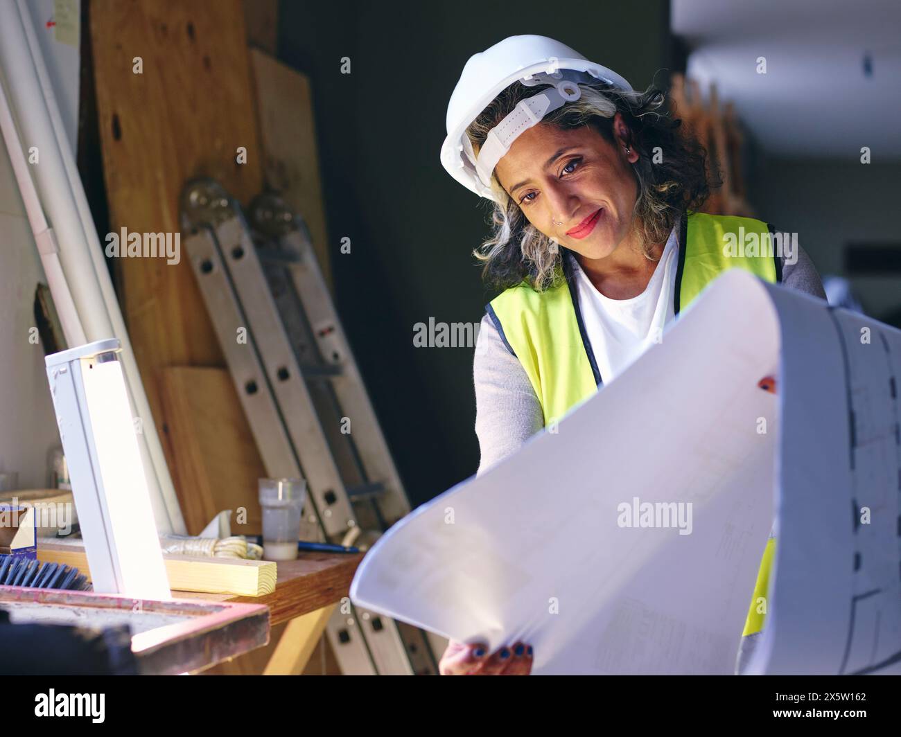 Woman in hardhat looking at blueprint Stock Photo - Alamy