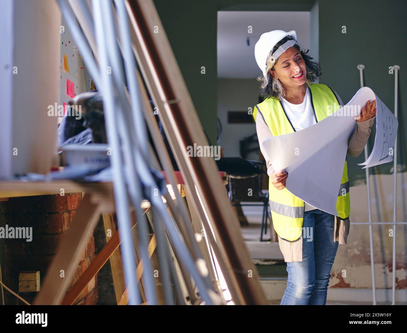 Woman in hardhat looking at blueprint Stock Photo - Alamy